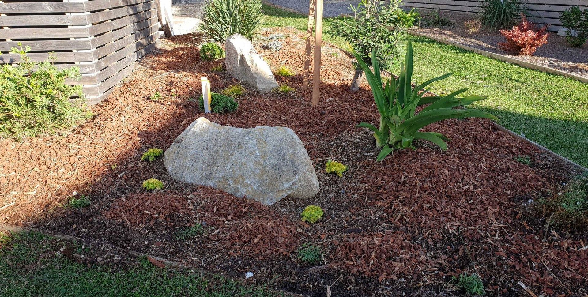 There is a large rock in the middle of the garden.