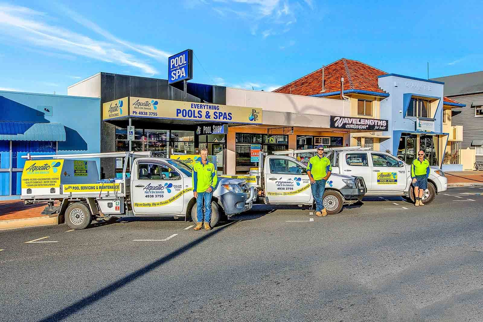A Group Of Men Are Standing Next To Their Trucks In Front Of A Building — Aquatic Pool & Spa Services In Yeppoon, QLD