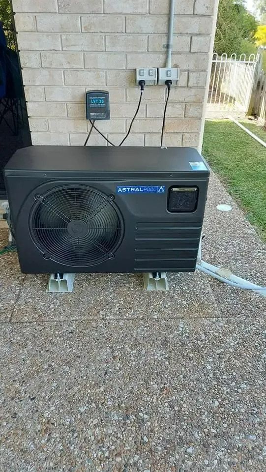 A Black Air Conditioner Is Sitting On Top Of A Gravel Driveway — Aquatic Pool & Spa Services In Yeppoon, QLD