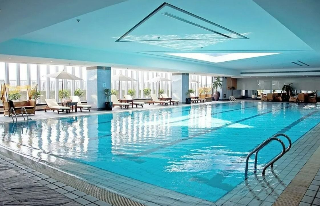 A Large Indoor Swimming Pool With Chairs Around It — Aquatic Pool & Spa Services In Yeppoon, QLD