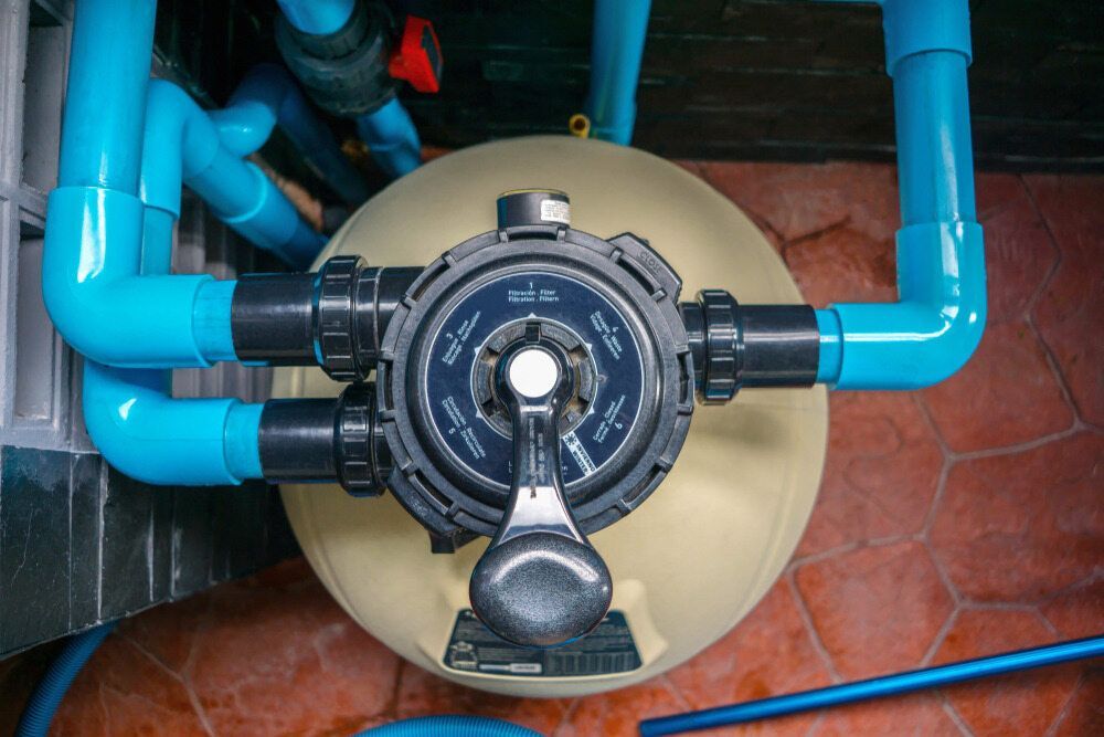 A Close Up Of A Swimming Pool Filter With Blue Pipes Around It — Aquatic Pool & Spa Services In Yeppoon, QLD