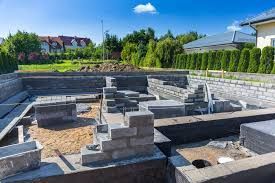 Foundation of a building under construction, featuring gray cinder blocks and exposed earth.
