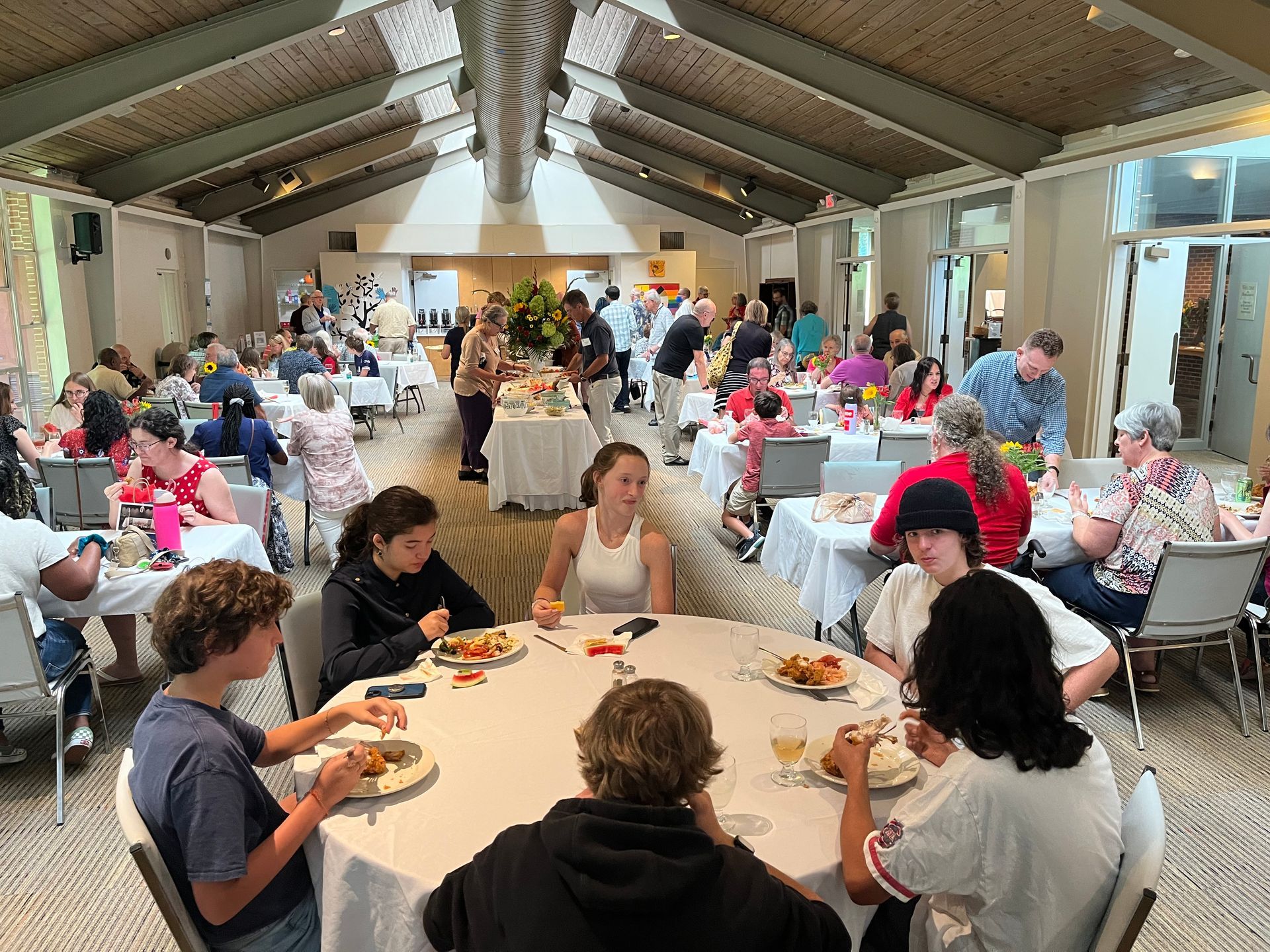 A group of people are sitting at tables in a large room eating food.