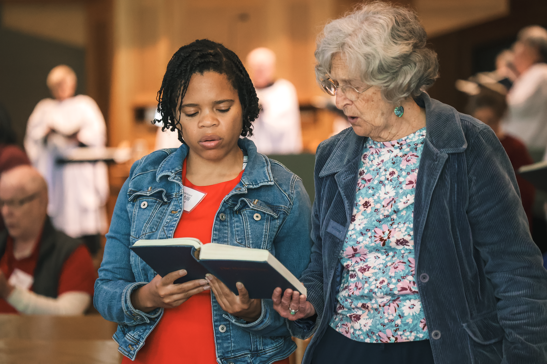 Two women are looking at a book together in a church.