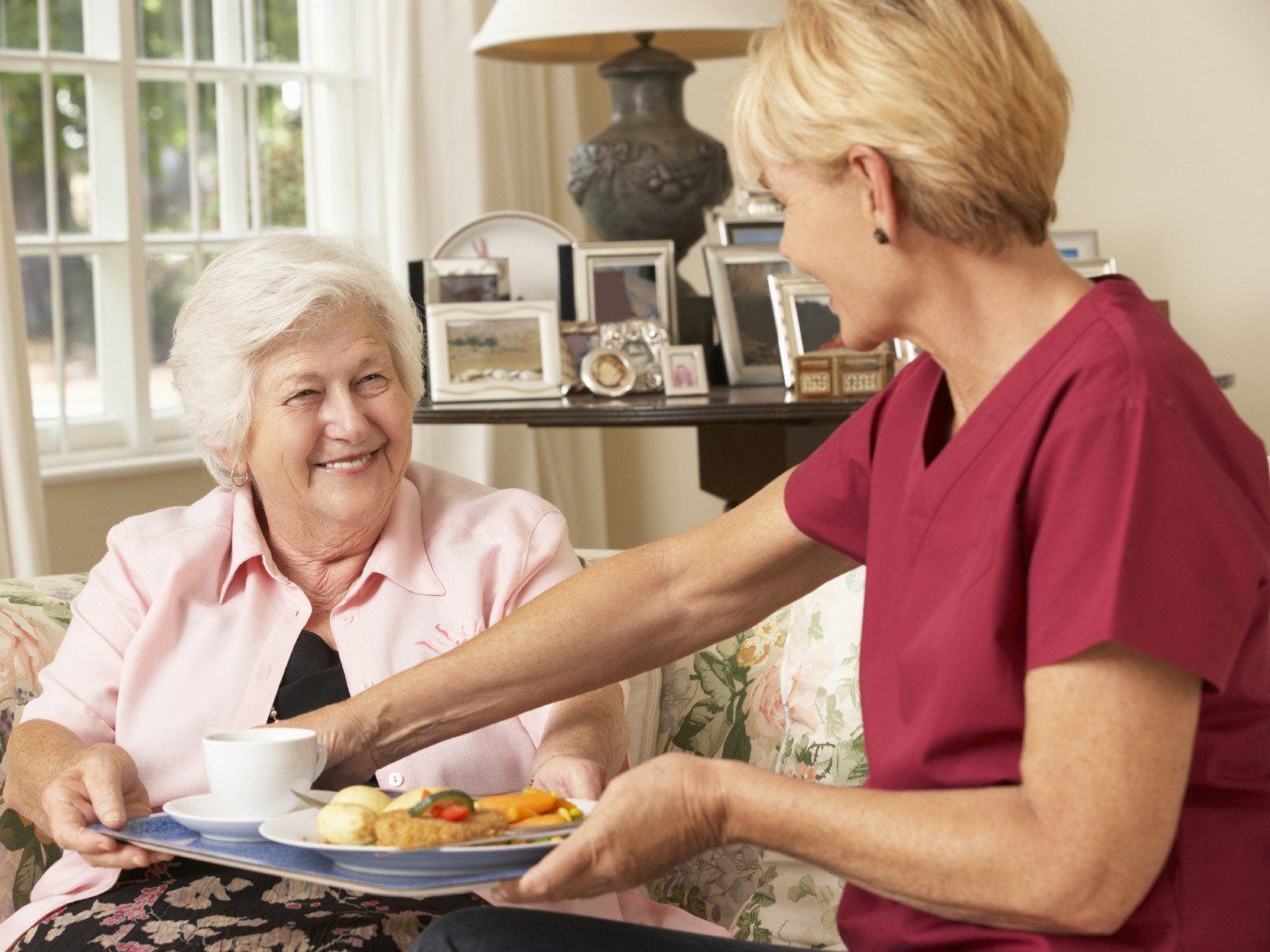 Caregiver giving meal to an elderly woman
