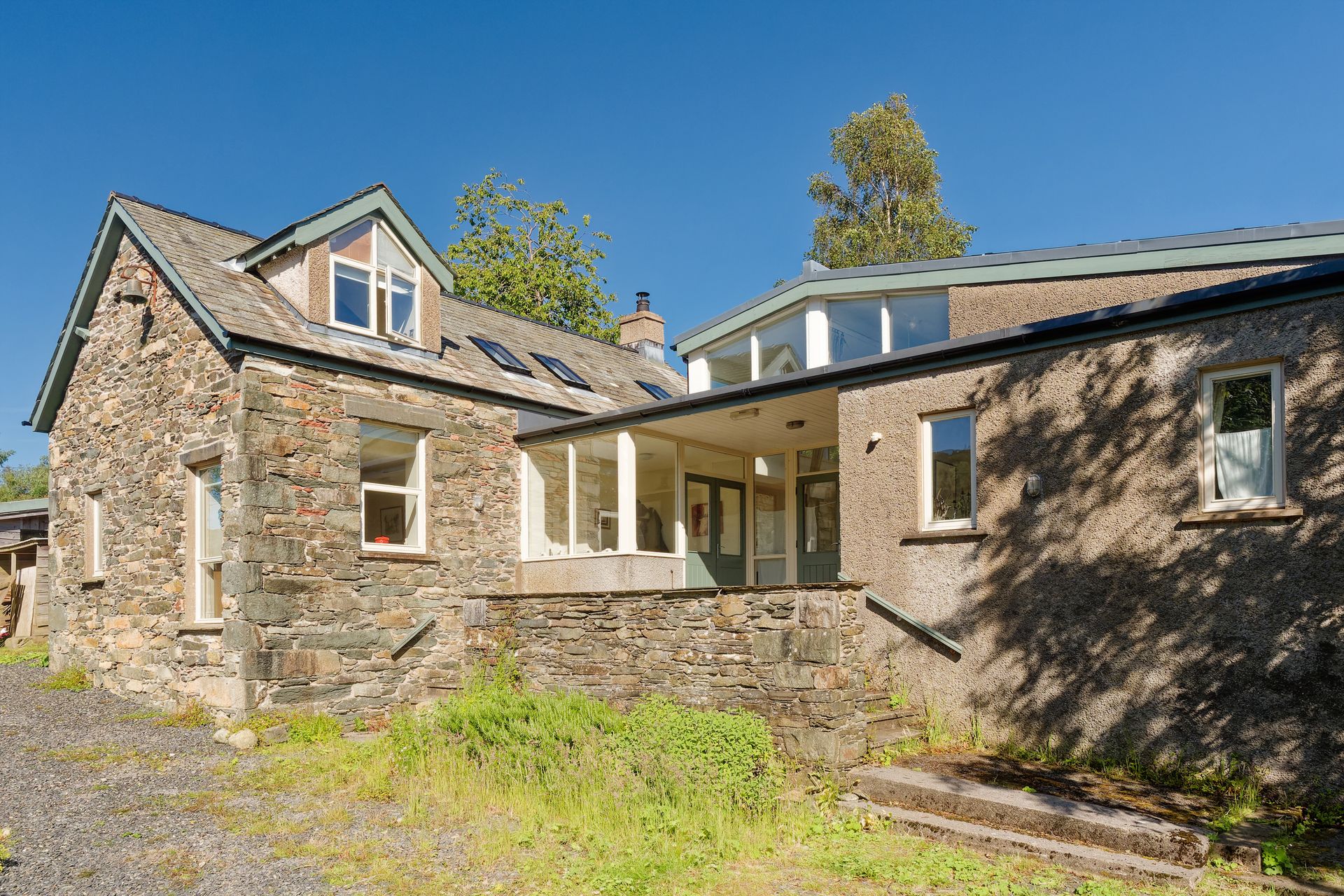 A large stoneformer school with a porch and stairs in front of it.