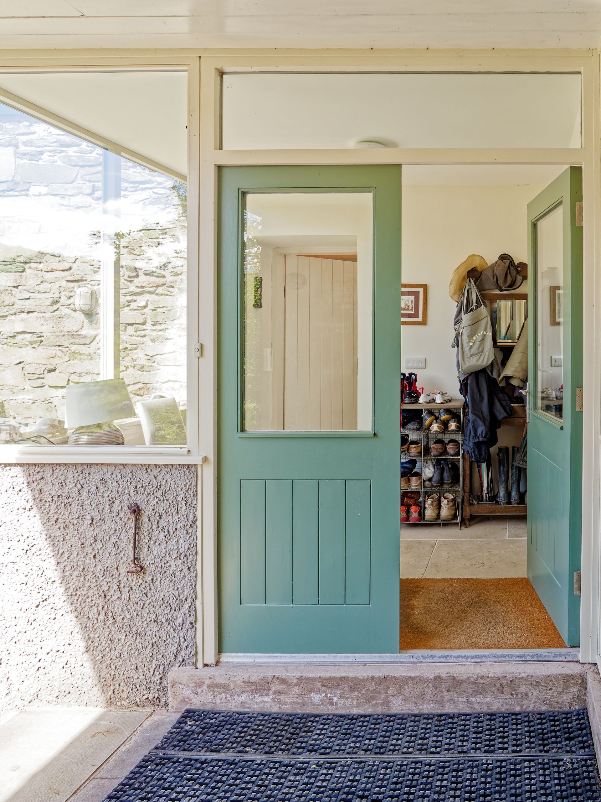 A green door is open to a room with a window.