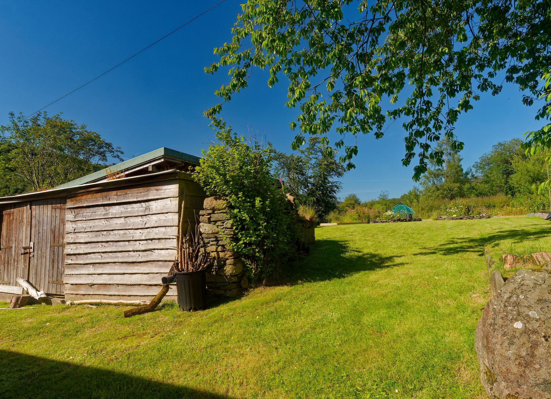 A wooden shed is sitting in the middle of a lush green field.