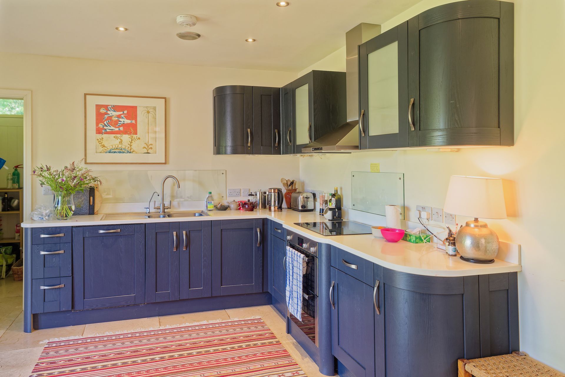 A kitchen with blue cabinets and a rug on the floor.
