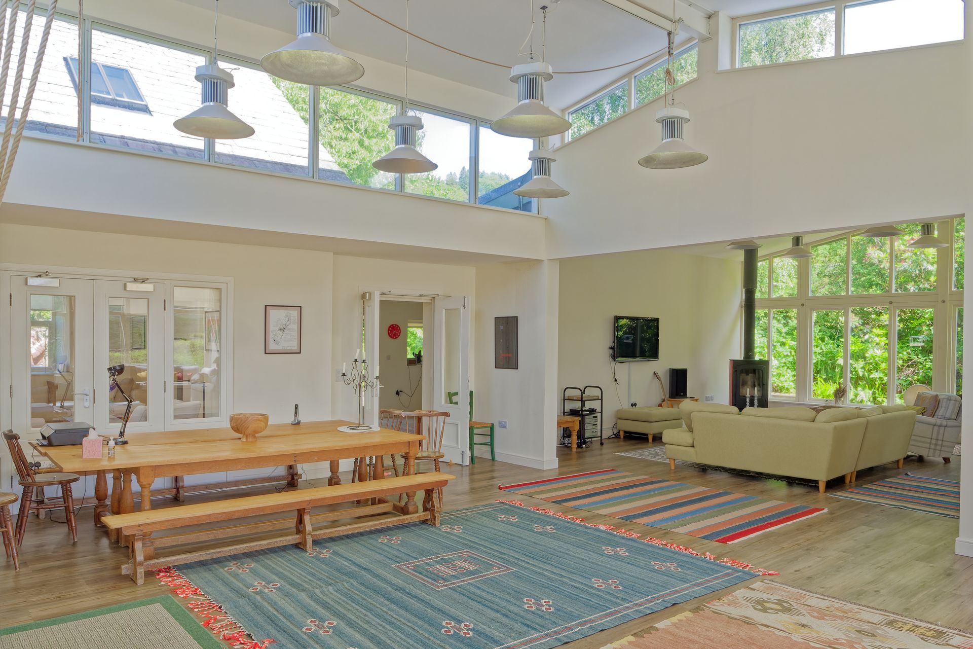 A large living room with a dining table and benches, beautiful views of the countryside