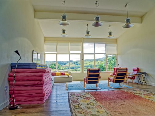 A living room with a lot of windows and chairs with a view of the fell hills