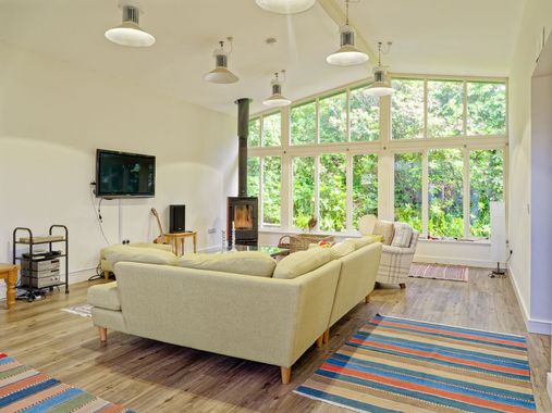 A living room with a large sectional sofa, a flat screen tv and a wood burner