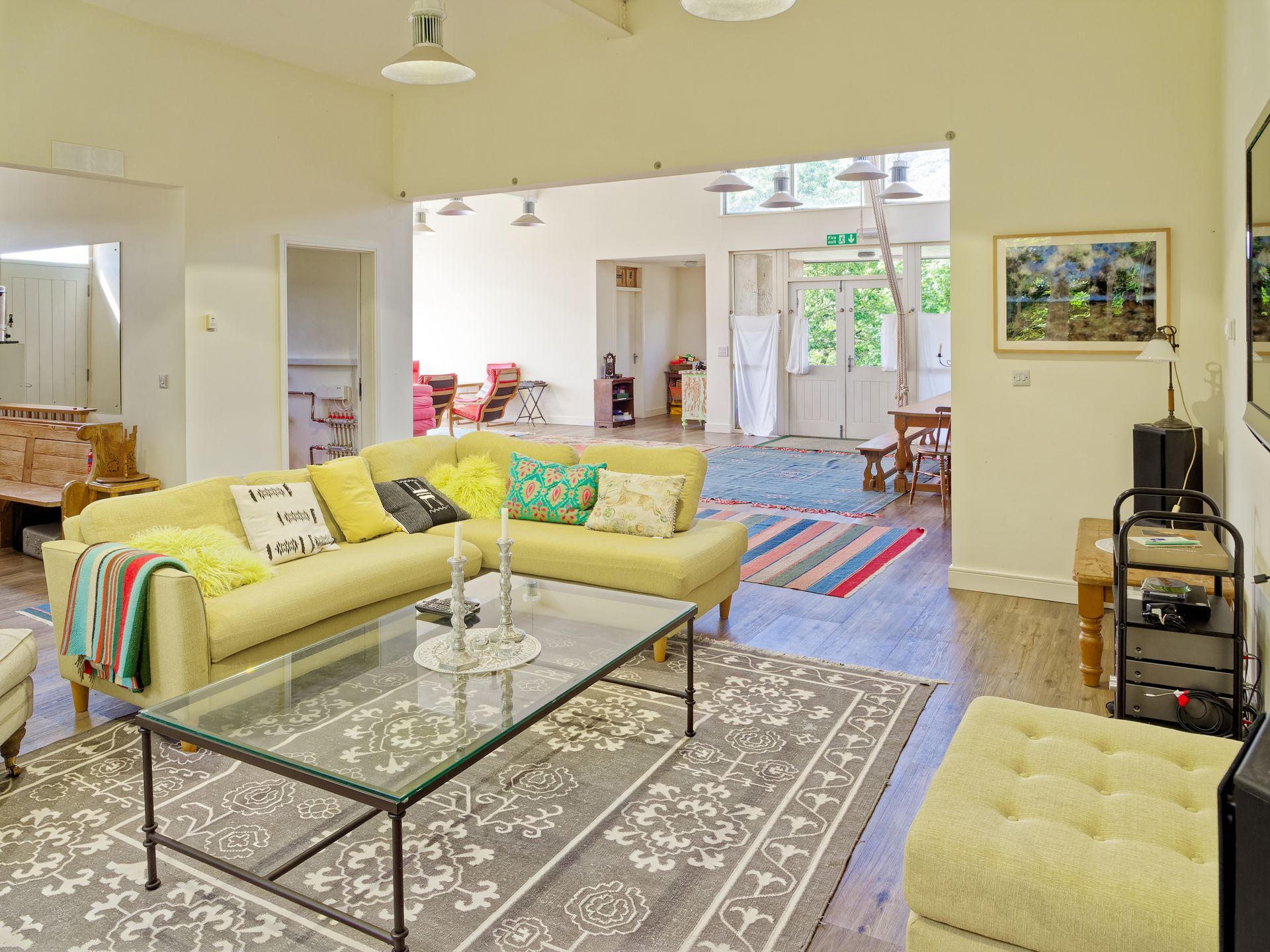 A living room with a yellow couch and a glass coffee table
