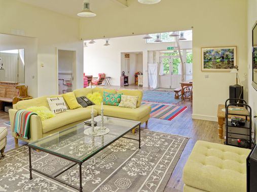 A living room with a yellow sofa and a glass coffee table