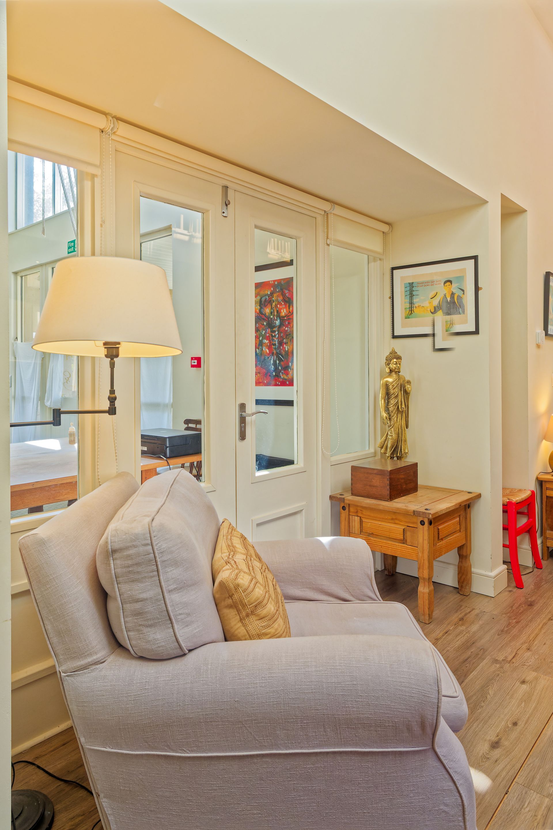 A living room with a chair , table , lamp and statue.