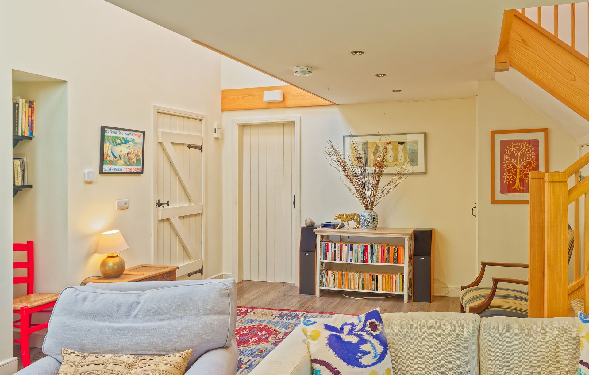 A living room with asofa , chair , bookshelf and stairs.