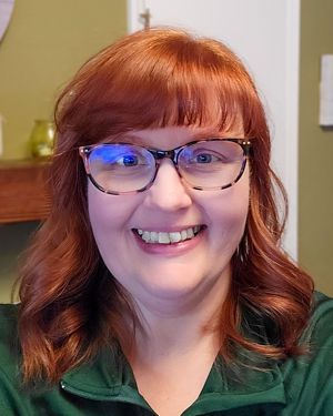 a woman wearing glasses and a green shirt is smiling for the camera .