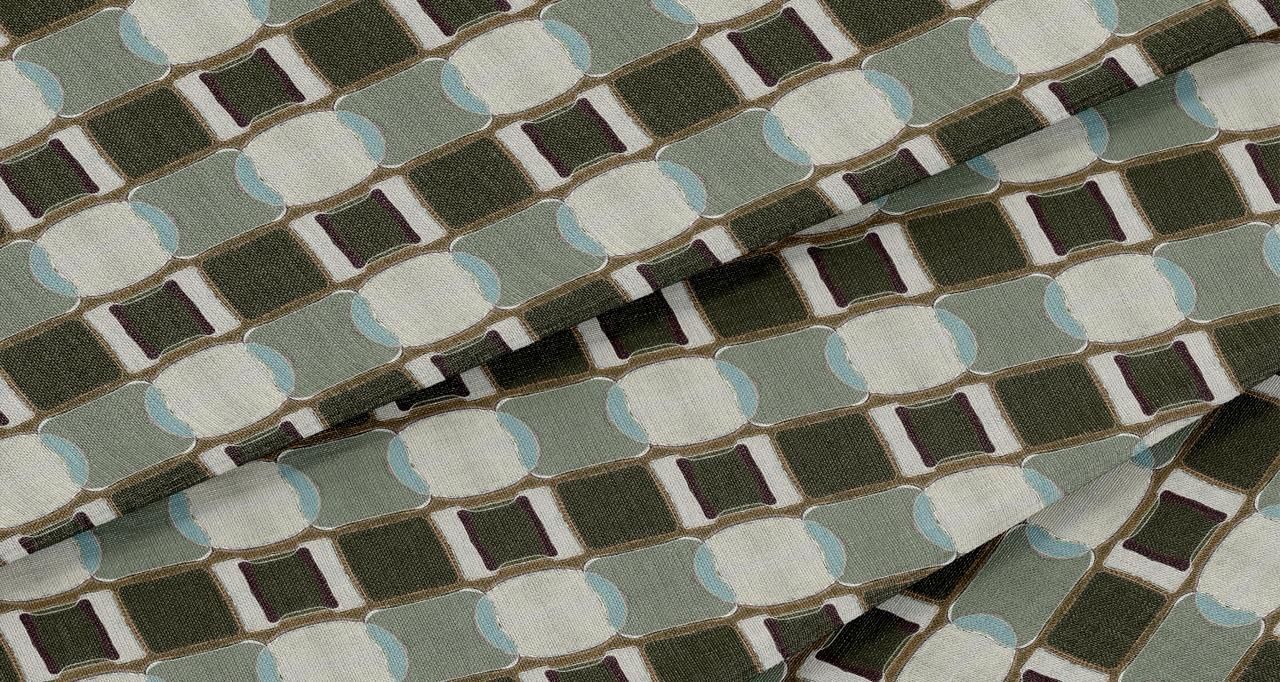 A close-up view of woven fabric featuring a repeating pattern of sage green, dark olive, white, and pale blue circles.
