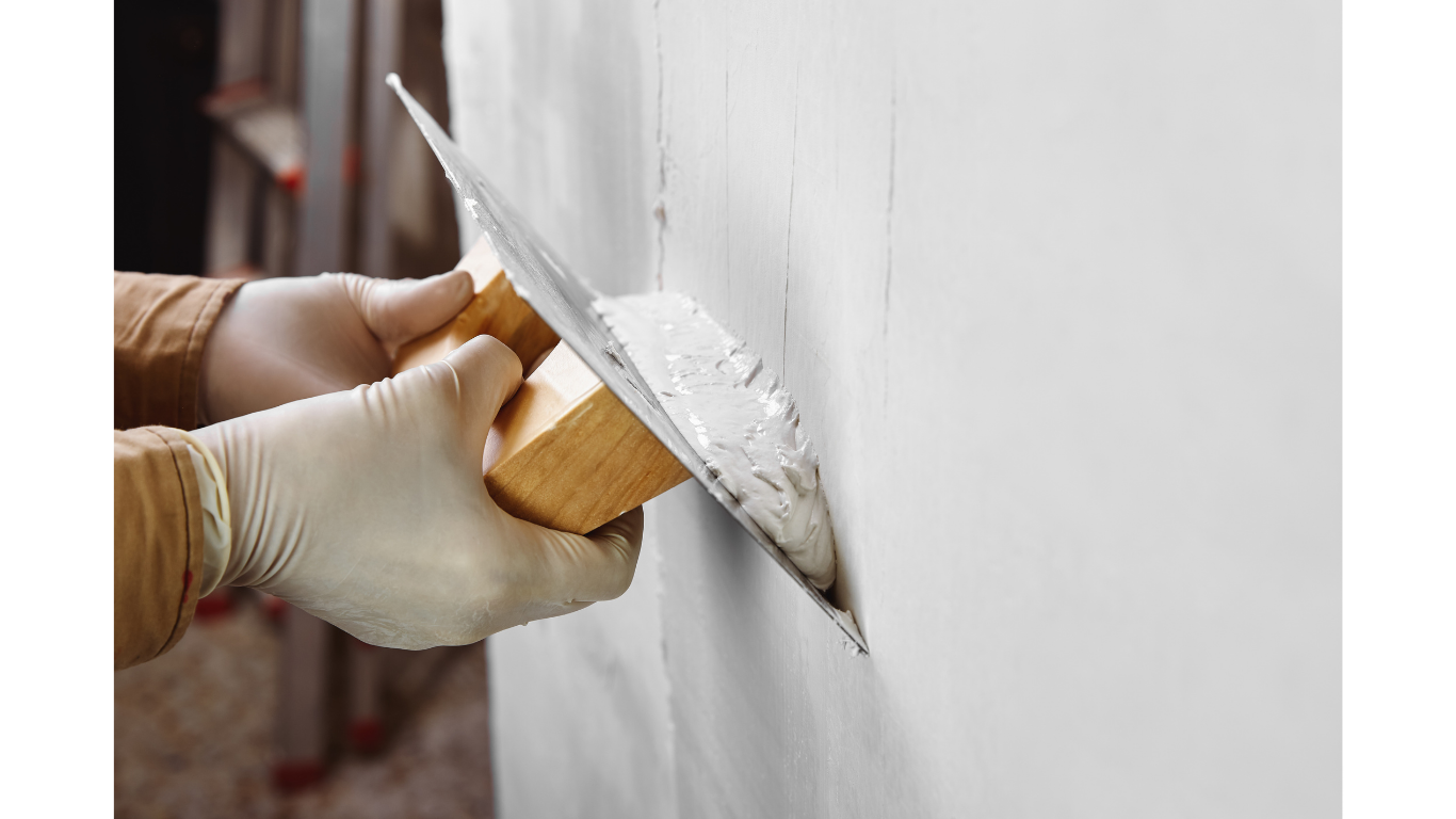 contractor applying plaster to wall with finishing trowel.