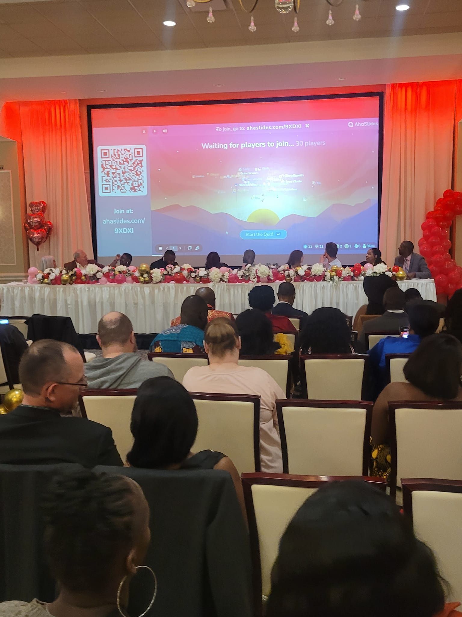 A group of people are sitting in front of a large screen