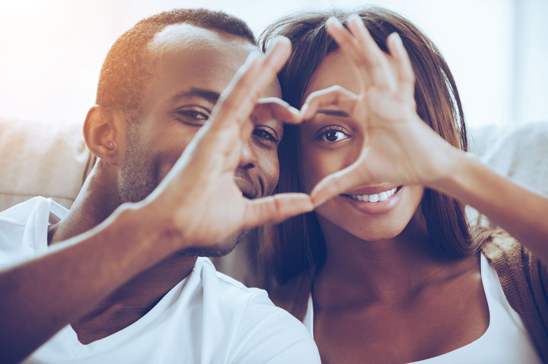 A man and a woman are making a heart shape with their hands.