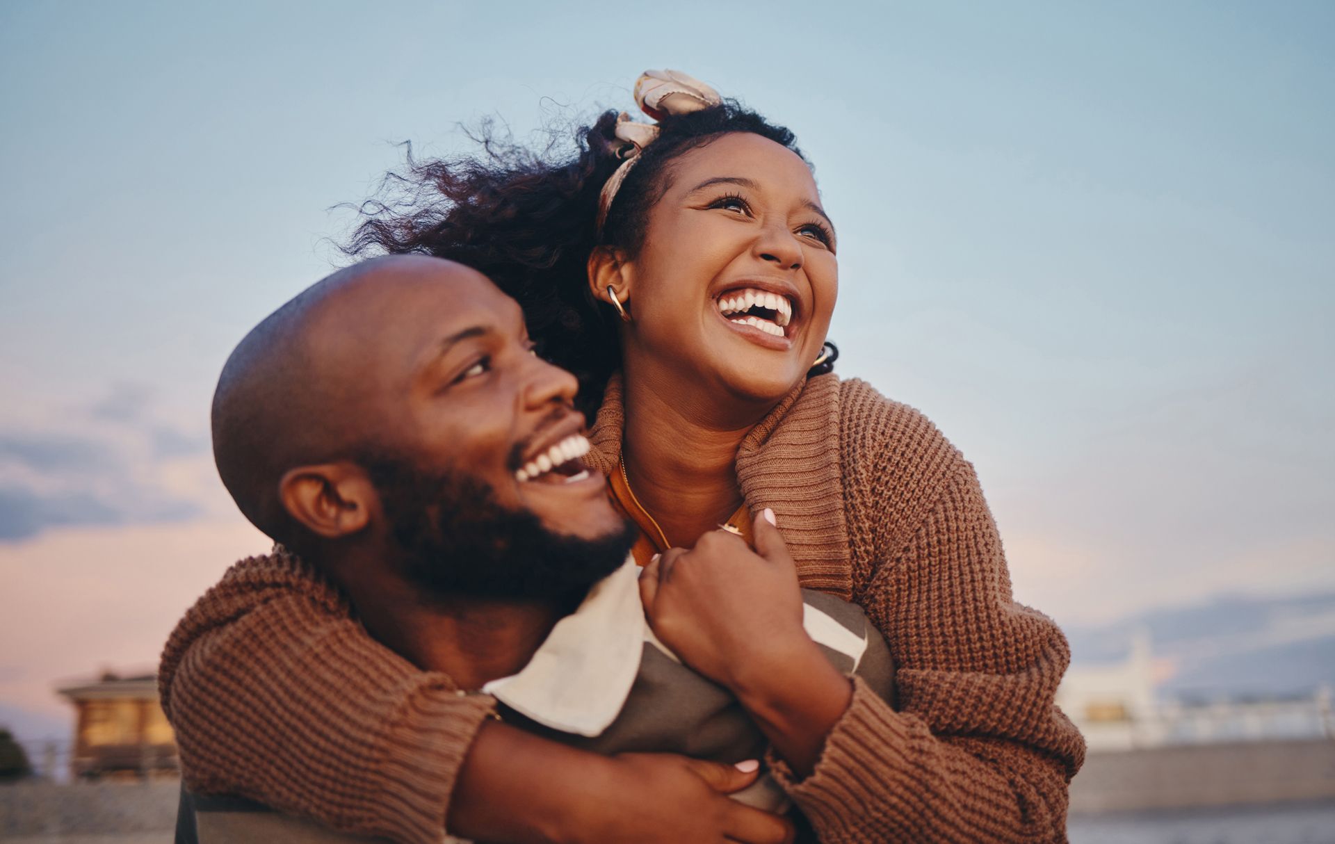 A man is carrying a woman on his back and they are laughing.