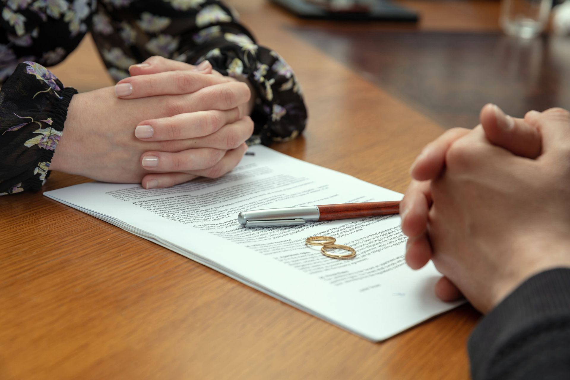 A man and a woman are sitting at a table with their hands folded over a piece of paper.