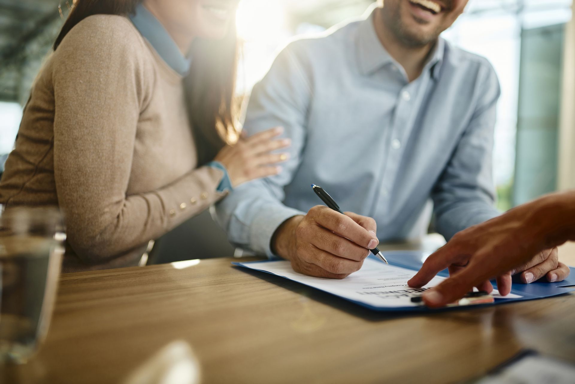 A man and a woman are sitting at a table signing a document.