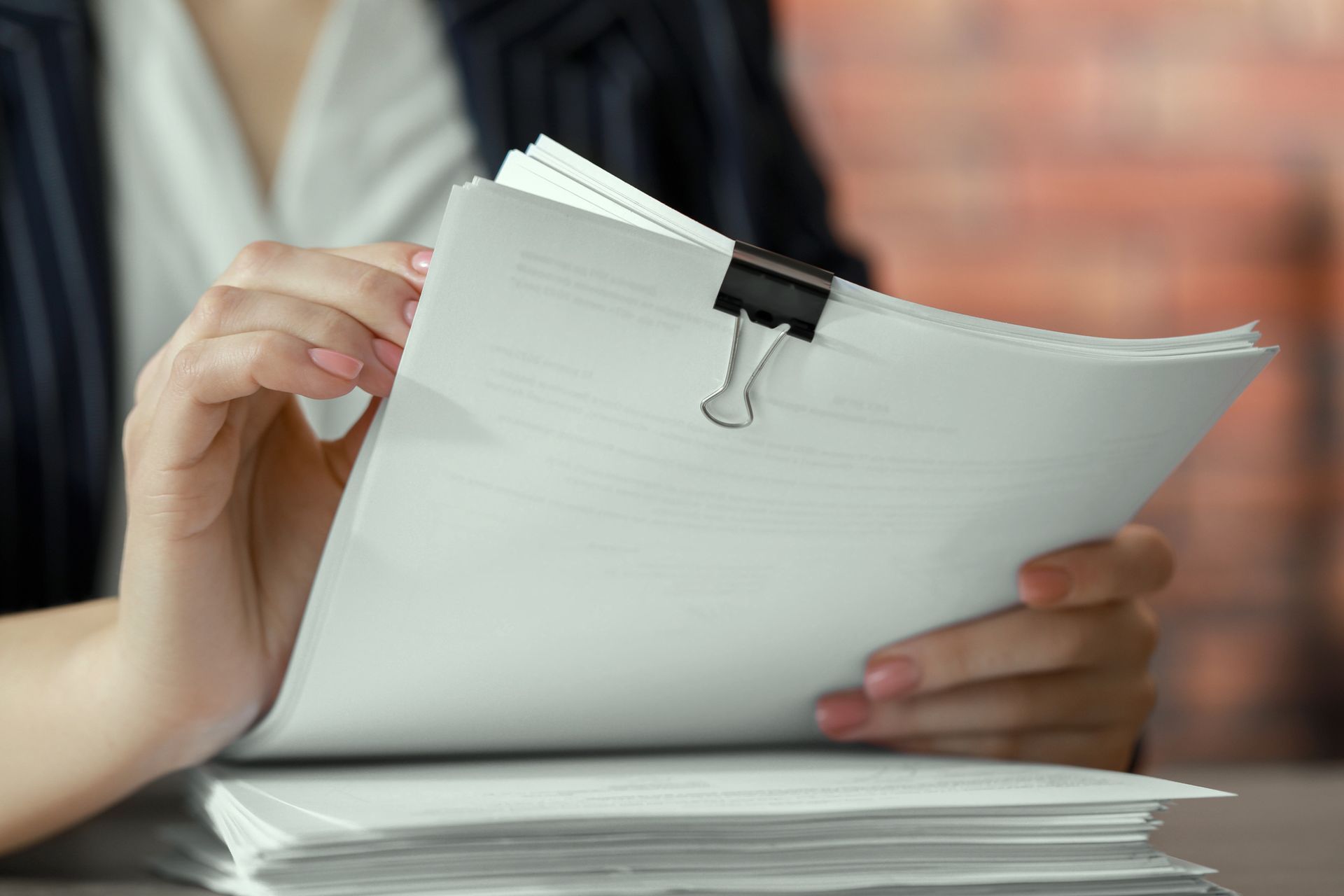 A woman is holding a piece of paper with a clip on it.