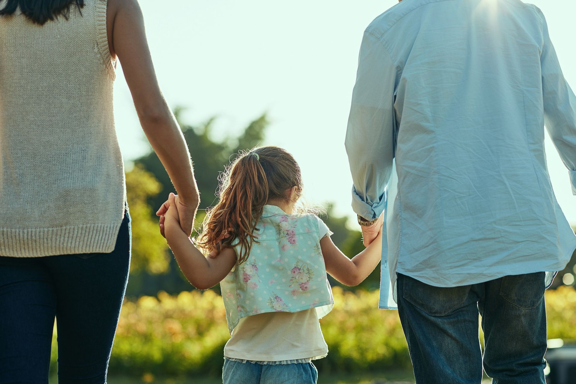 A family is holding hands while walking in a park.