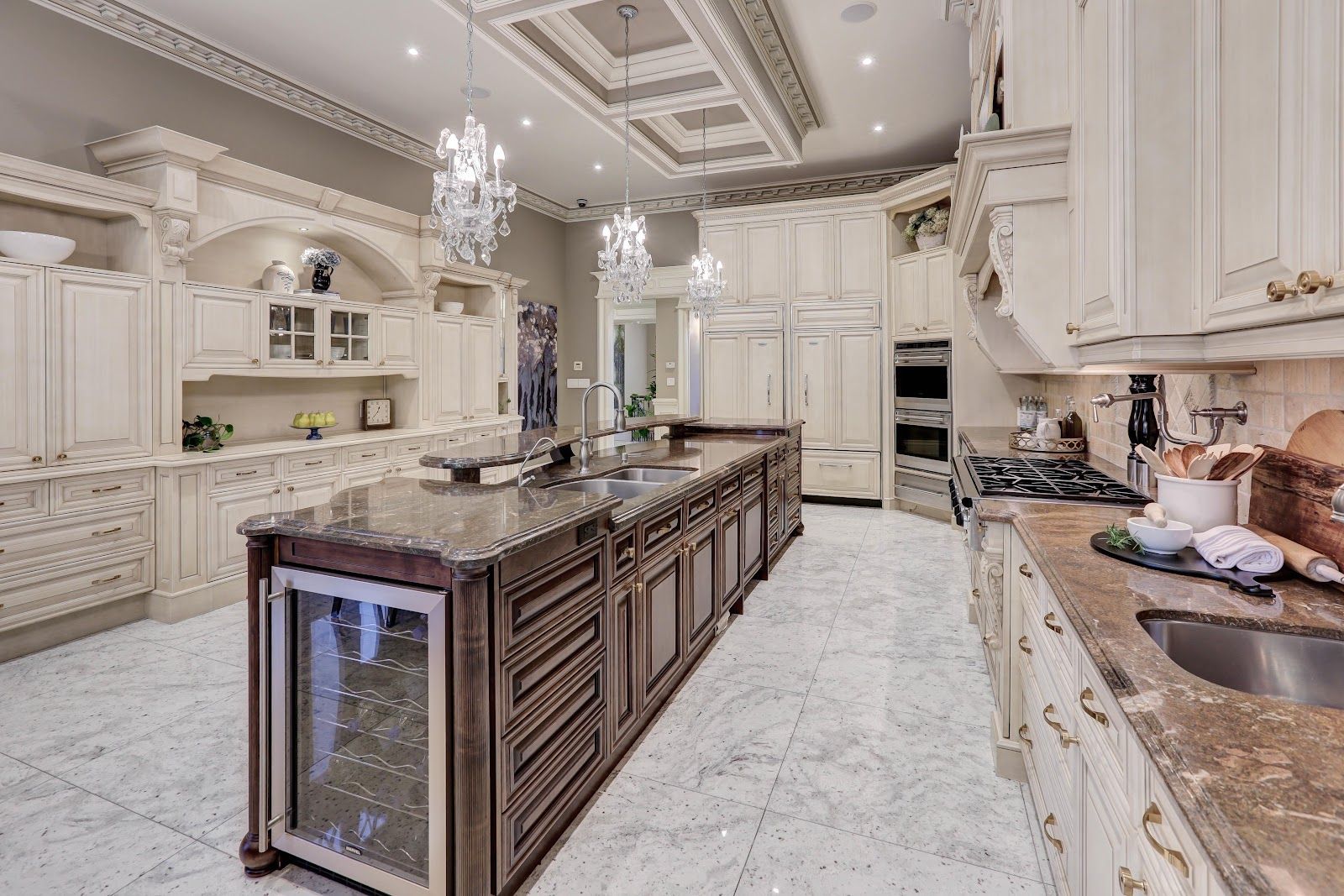 Luxurious kitchen with ornate cream cabinetry, large island, and marble flooring.