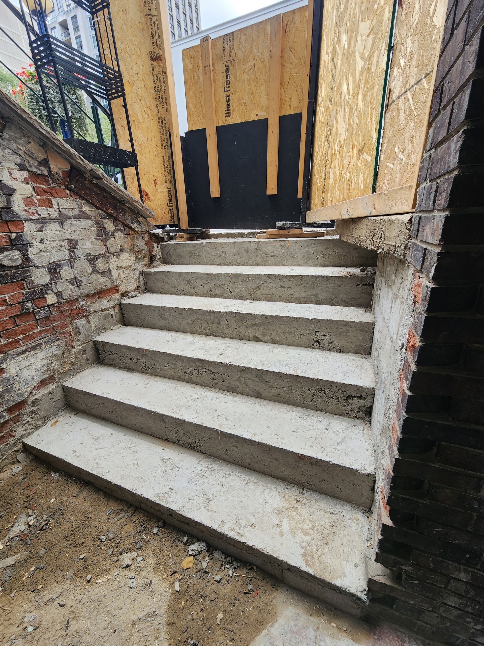 A set of concrete stairs leading up to a brick wall.