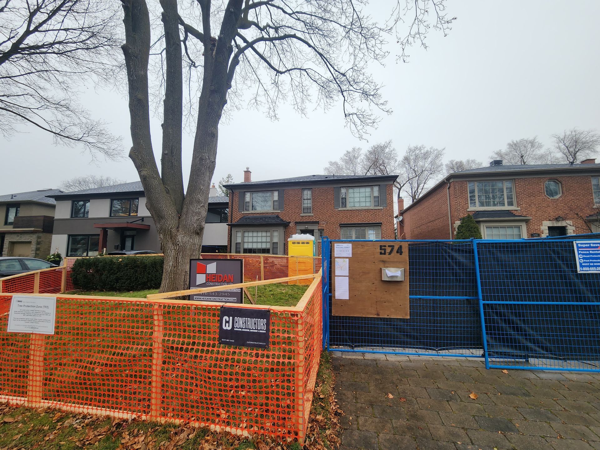 Construction site in front of a house at 874, with orange and blue fencing and a portable toilet.