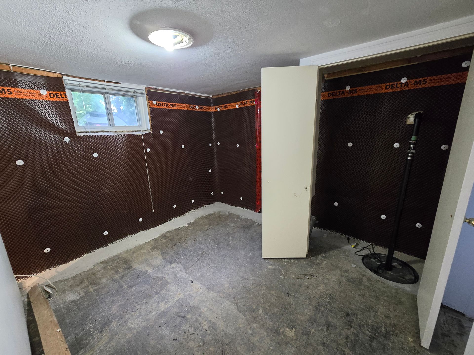 An empty basement with a window and a microphone.