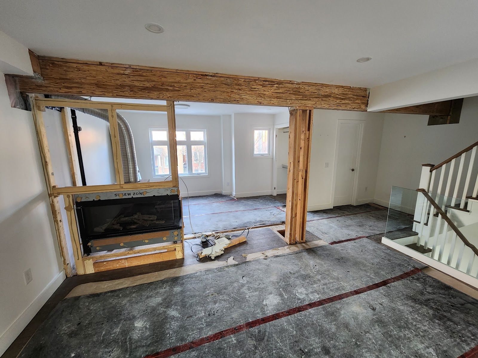 Interior room undergoing renovation, with exposed beams and unfinished walls, featuring a partially built fireplace.