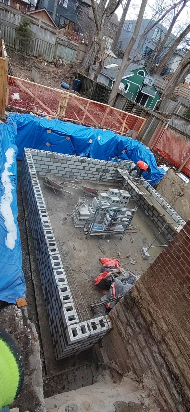 A brick wall is being built in a backyard.