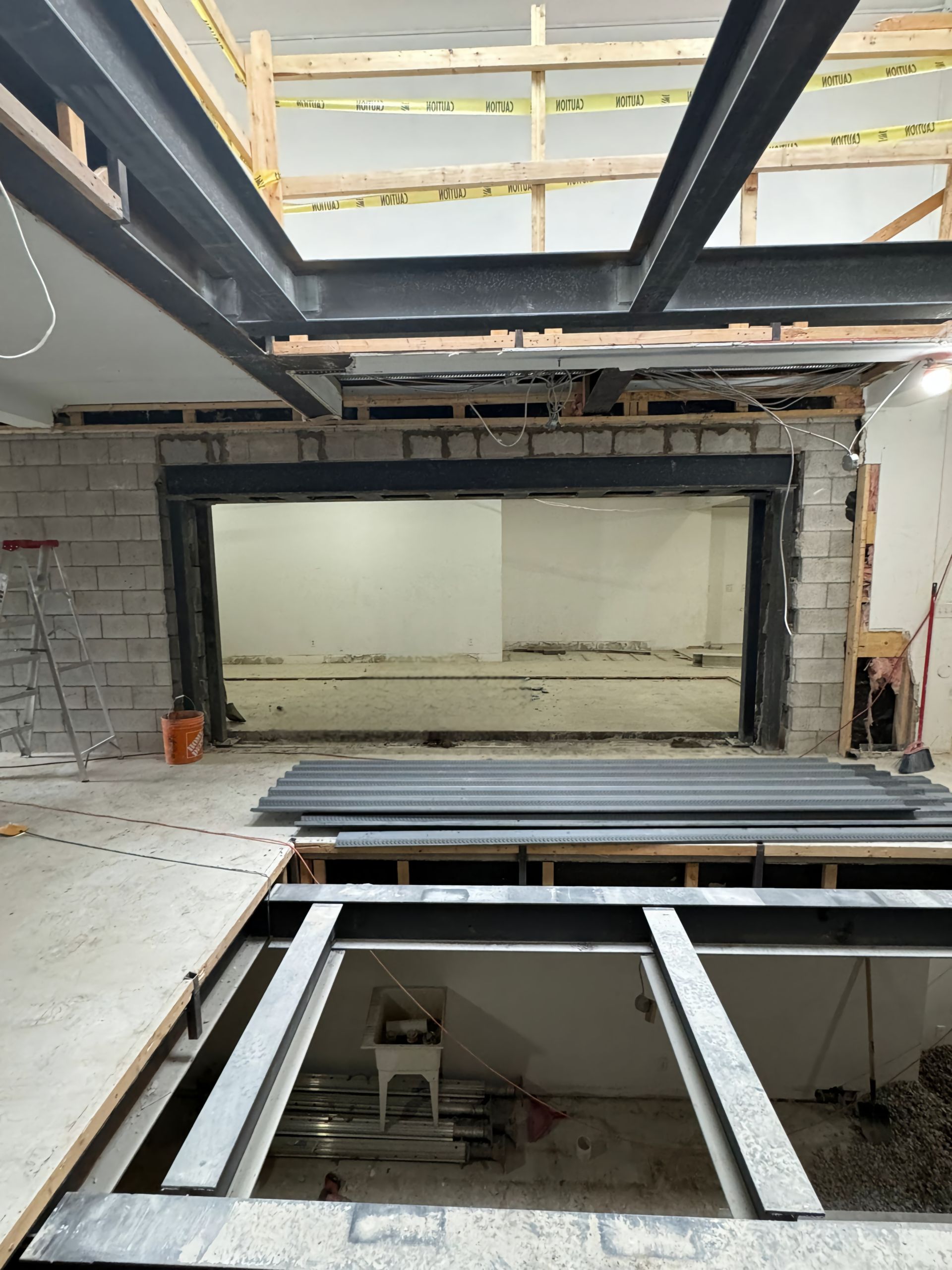 Interior construction site: exposed steel beams and concrete blocks frame an open doorway.