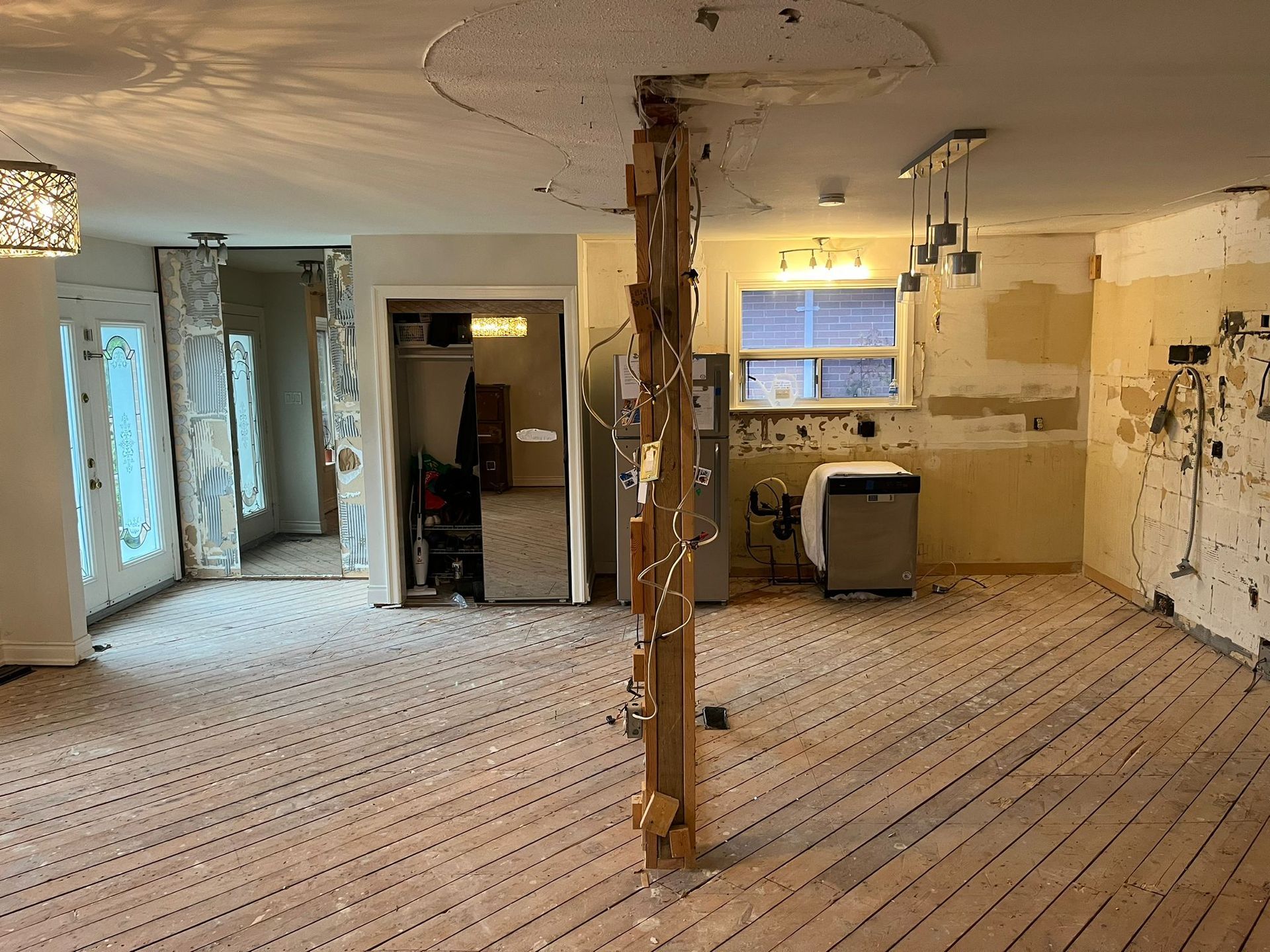 Interior renovation in progress; exposed studs, partial demolition of walls and ceiling, kitchen area visible.