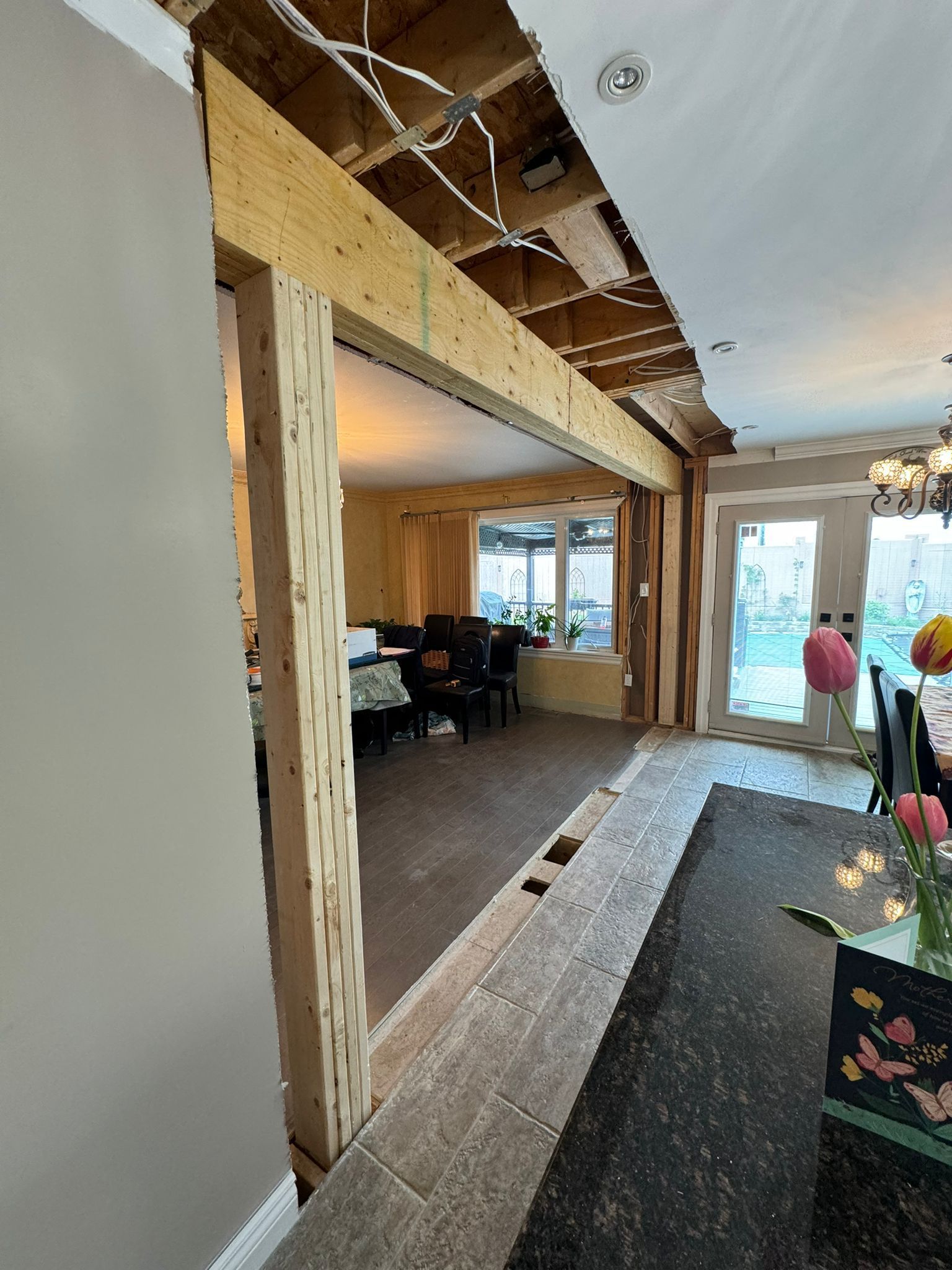 Interior home renovation; exposed framing with a view of a dining area, and wires visible.
