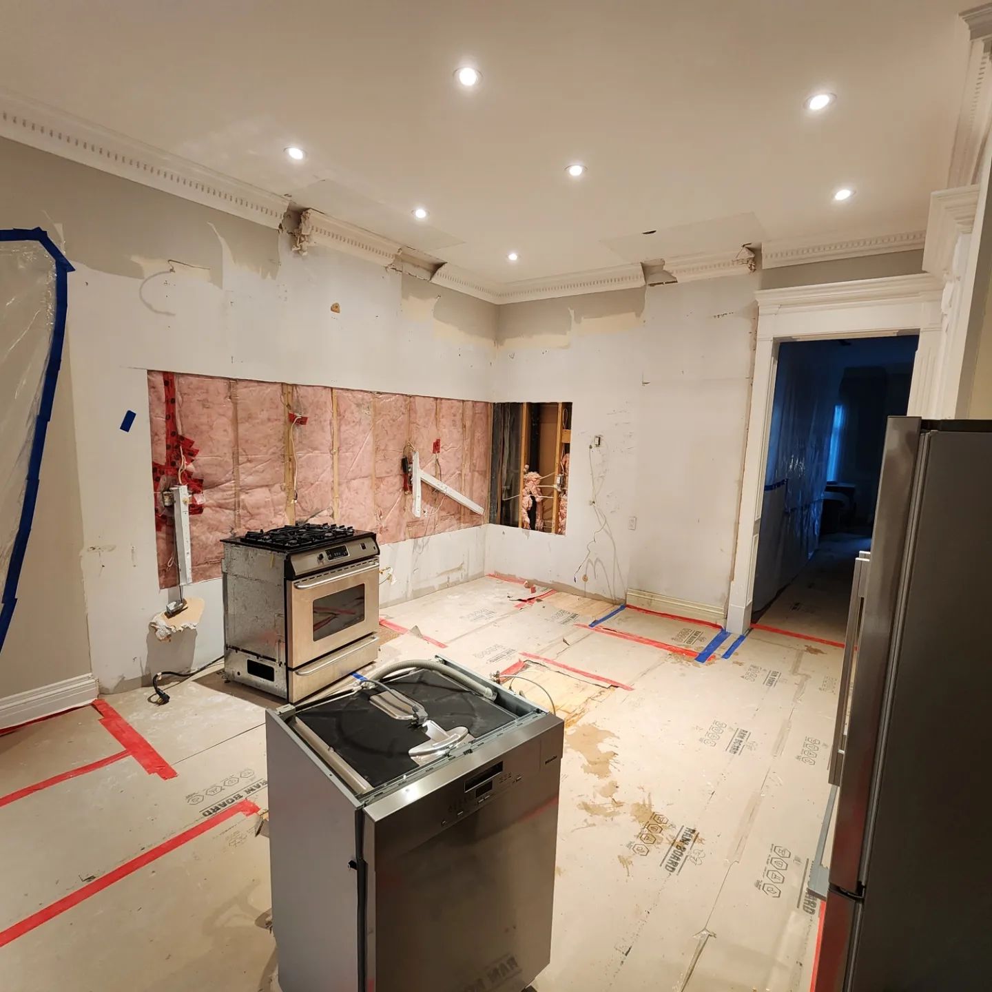 Kitchen under renovation: exposed walls, appliances, and insulation visible.
