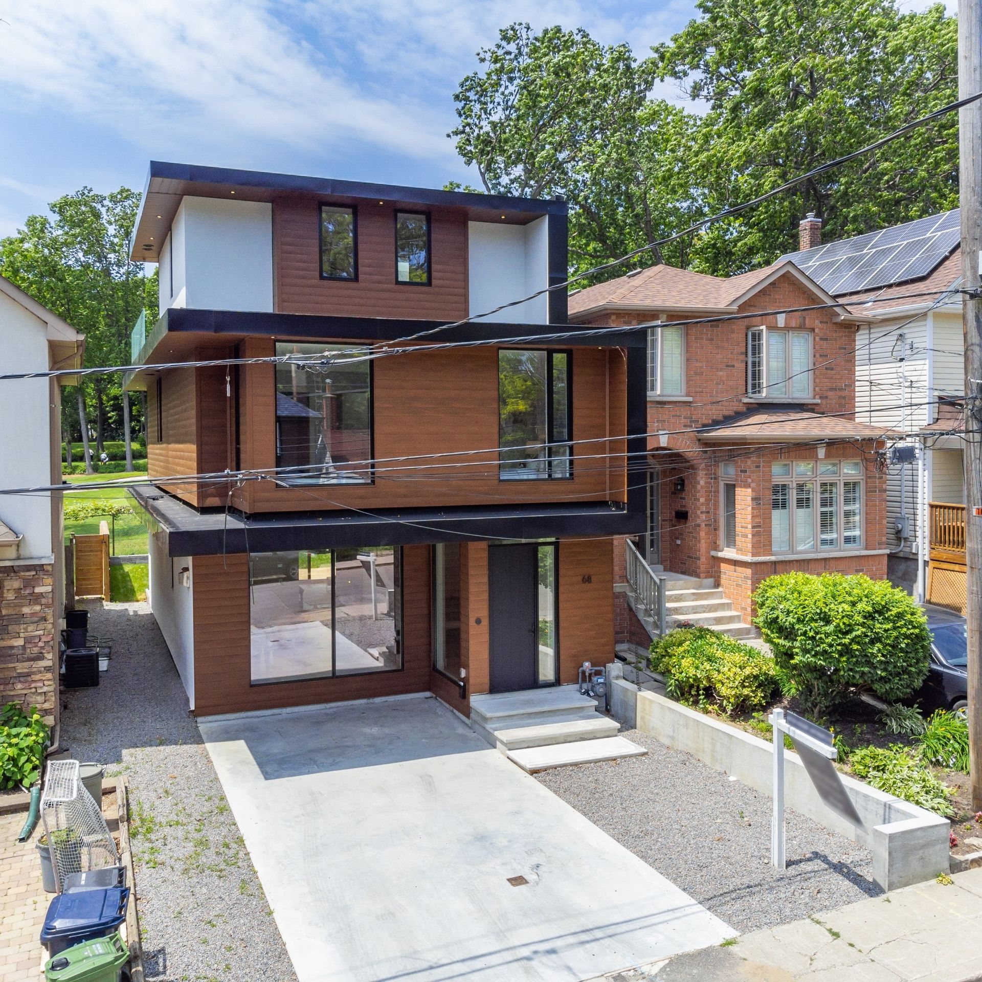 Modern three-story house with brown and white siding, black trim, and a concrete driveway.