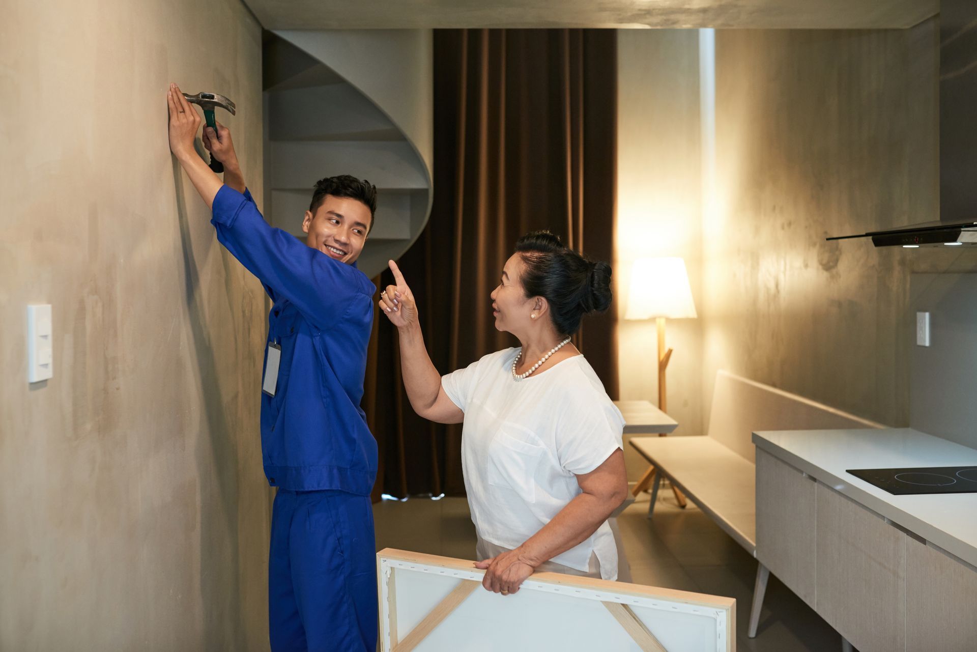 A man and a woman are hanging a picture on a wall.