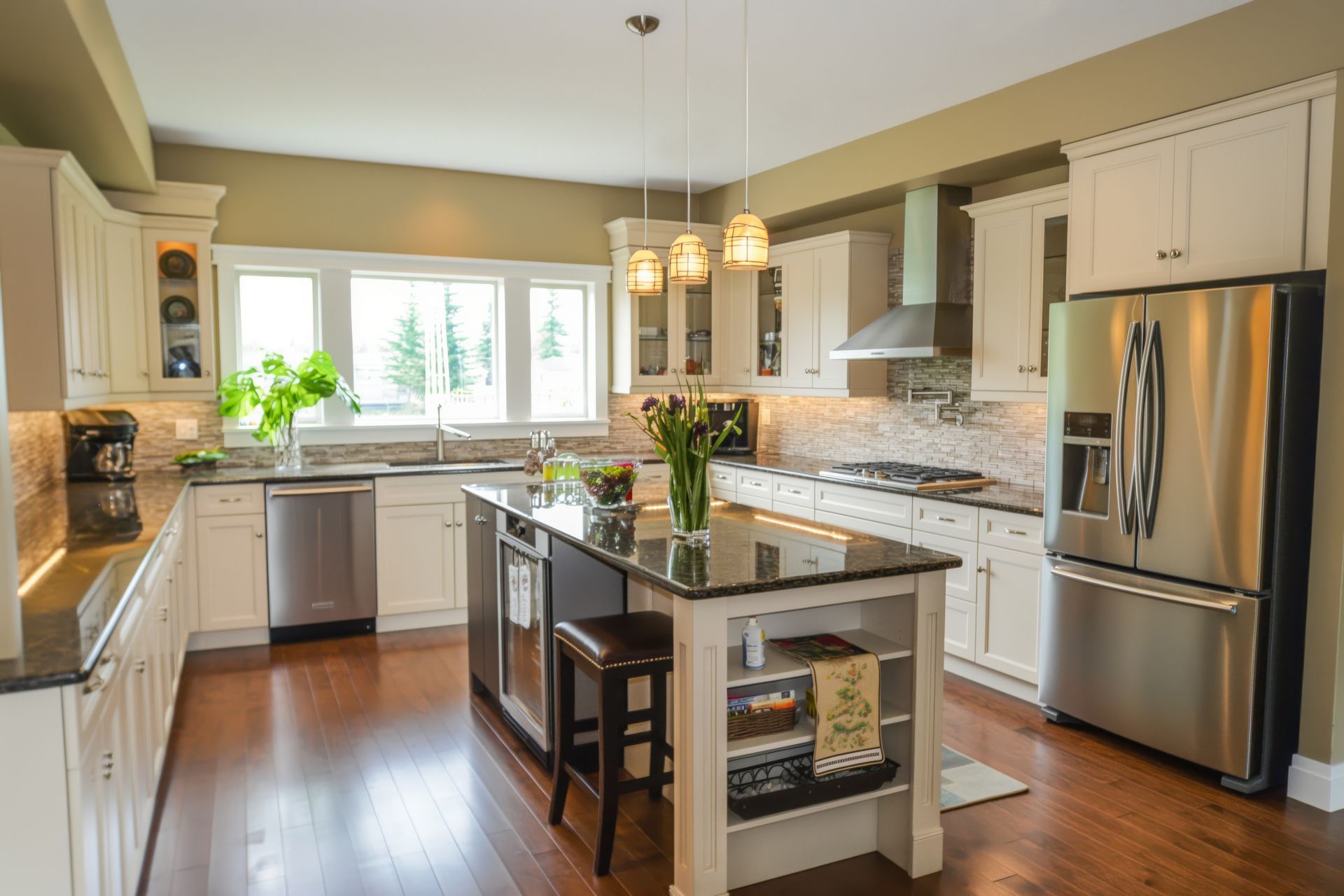 A kitchen with stainless steel appliances , white cabinets , hardwood floors and a large island.