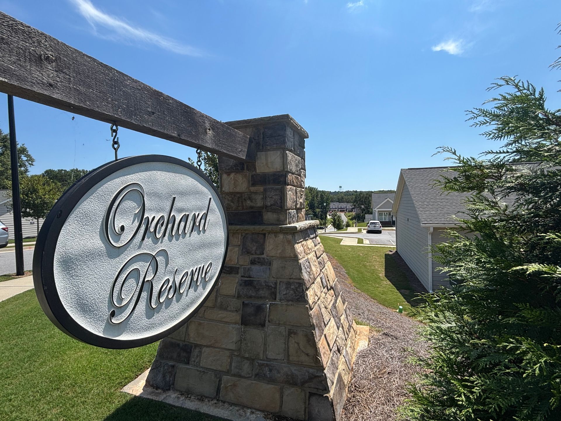 Stone entrance sign for Orchard Park with a circular logo, under a blue sky