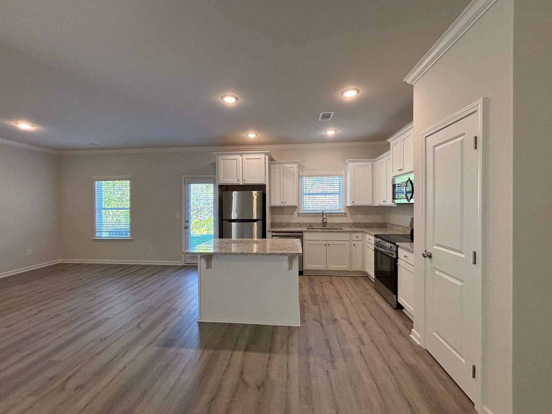 Open-concept kitchen and living room with gray floors, white cabinets, and island.