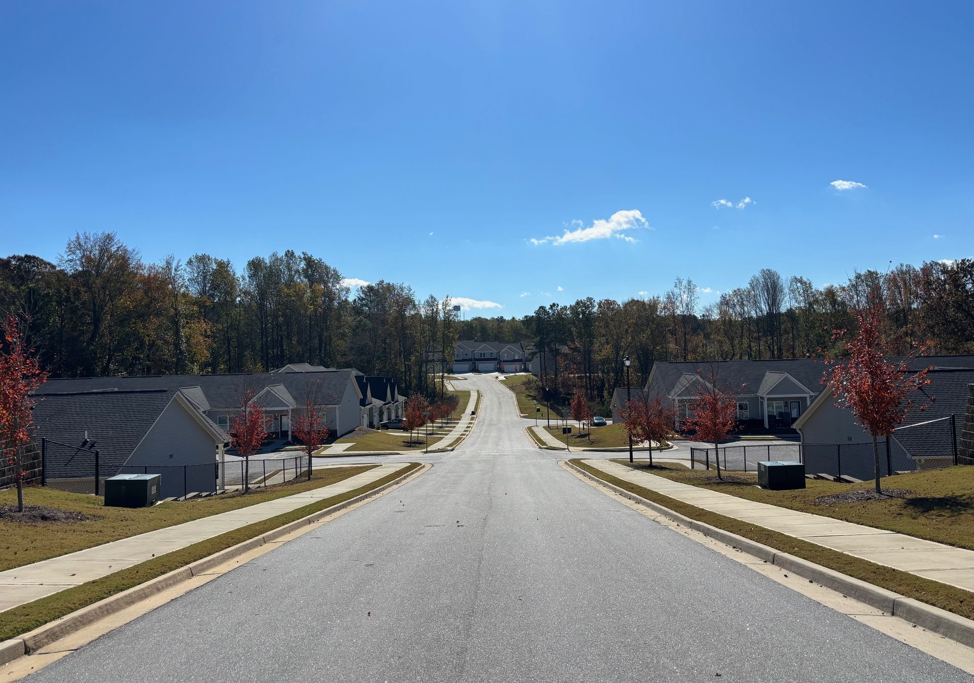 Suburban street descending between houses under a clear blue sky