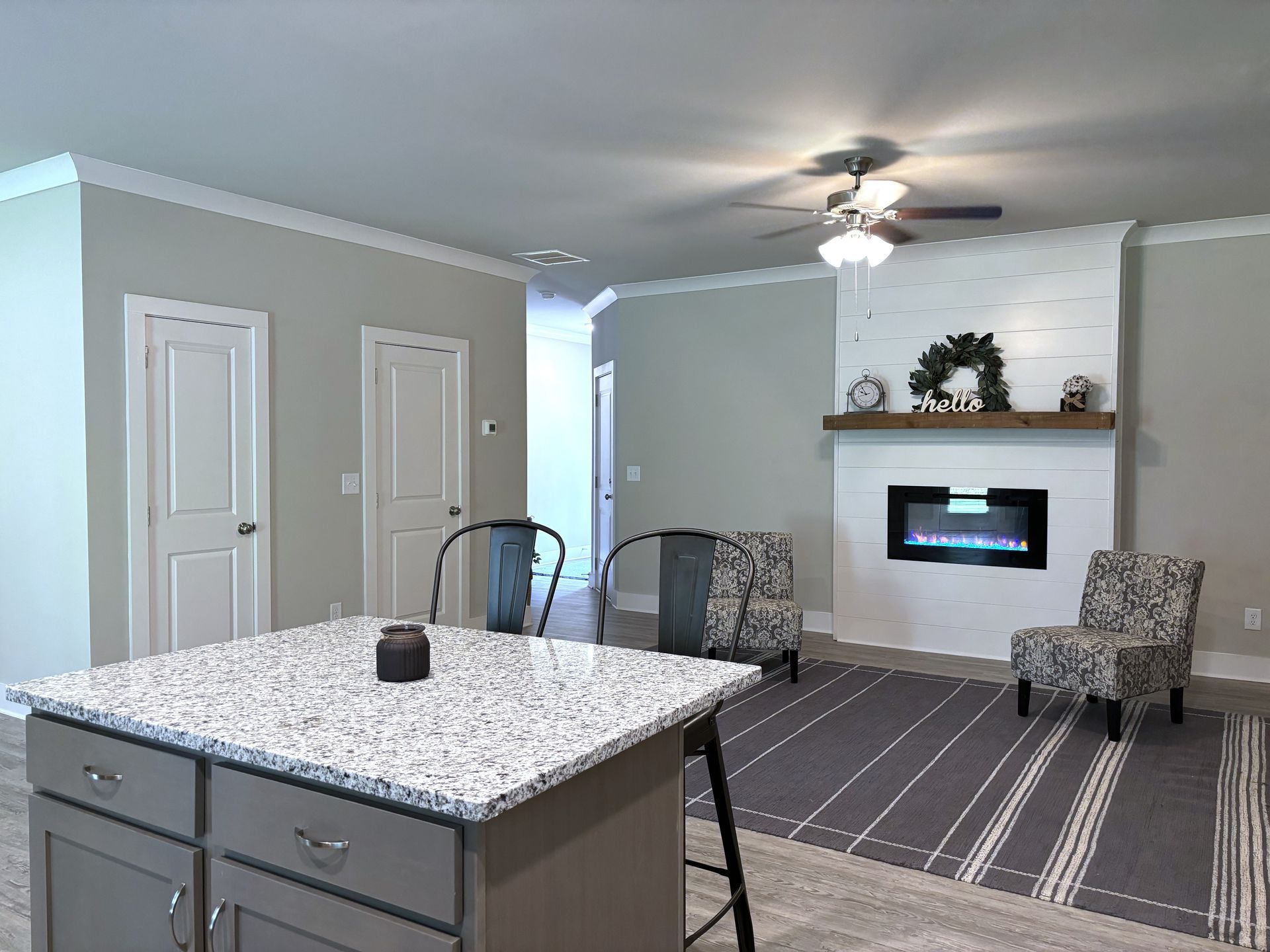 Modern living room with fireplace, striped rug, chairs, and a kitchen island in the foreground