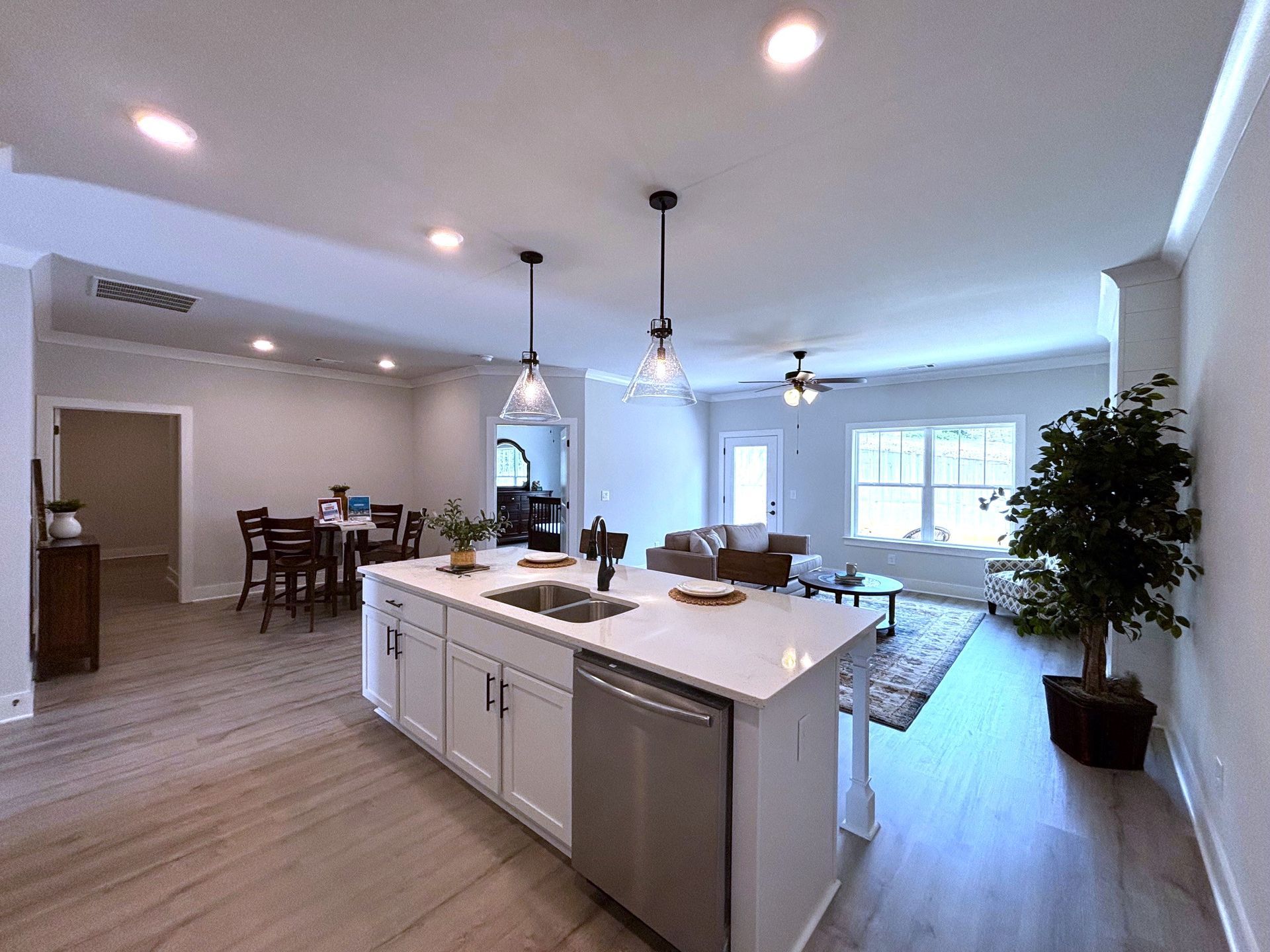 Open-plan kitchen and living room with island, pendant lights, gray floors, and large windows