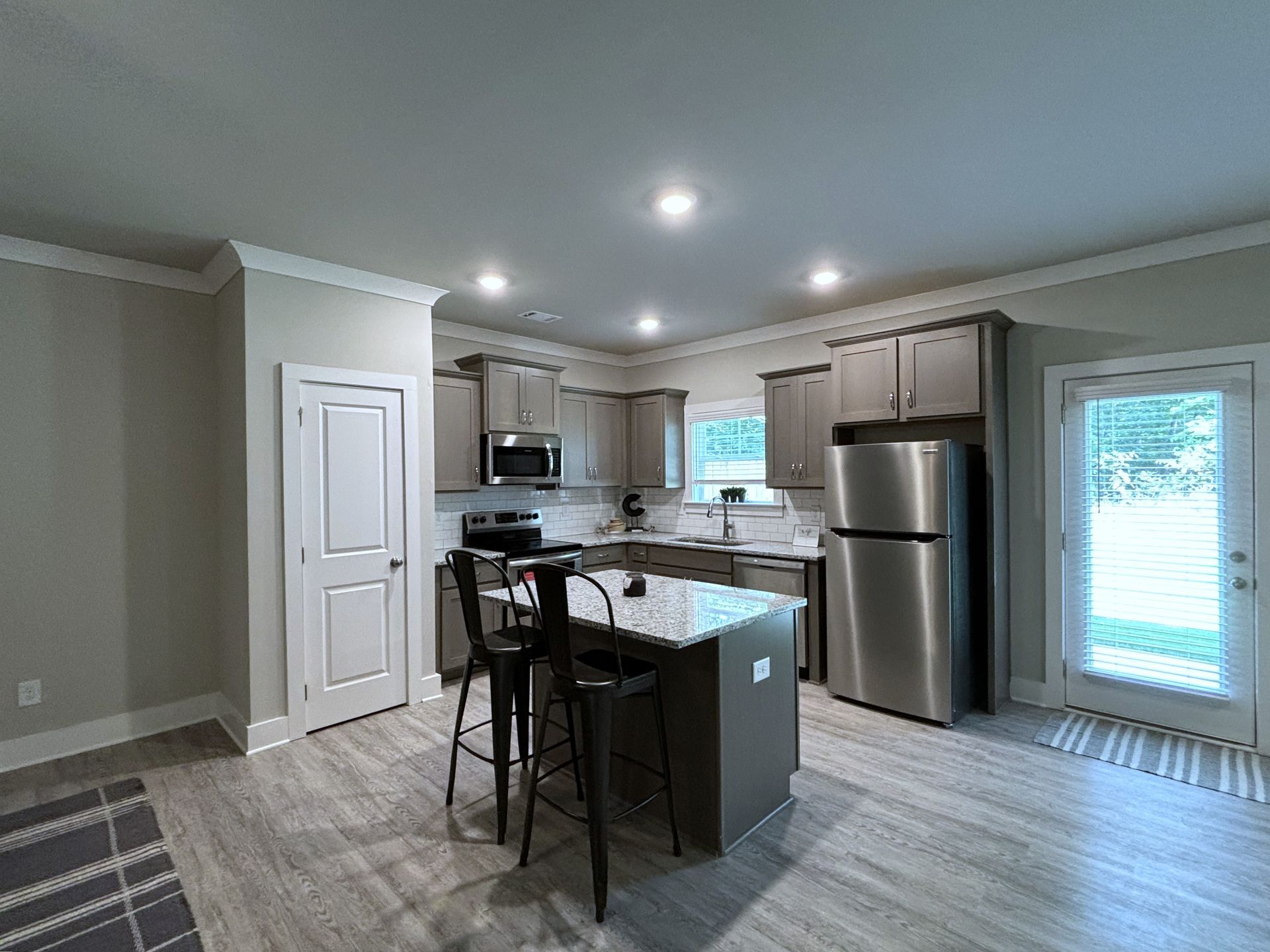 Modern kitchen with stainless steel appliances, granite island, bar stools, and light wood cabinets