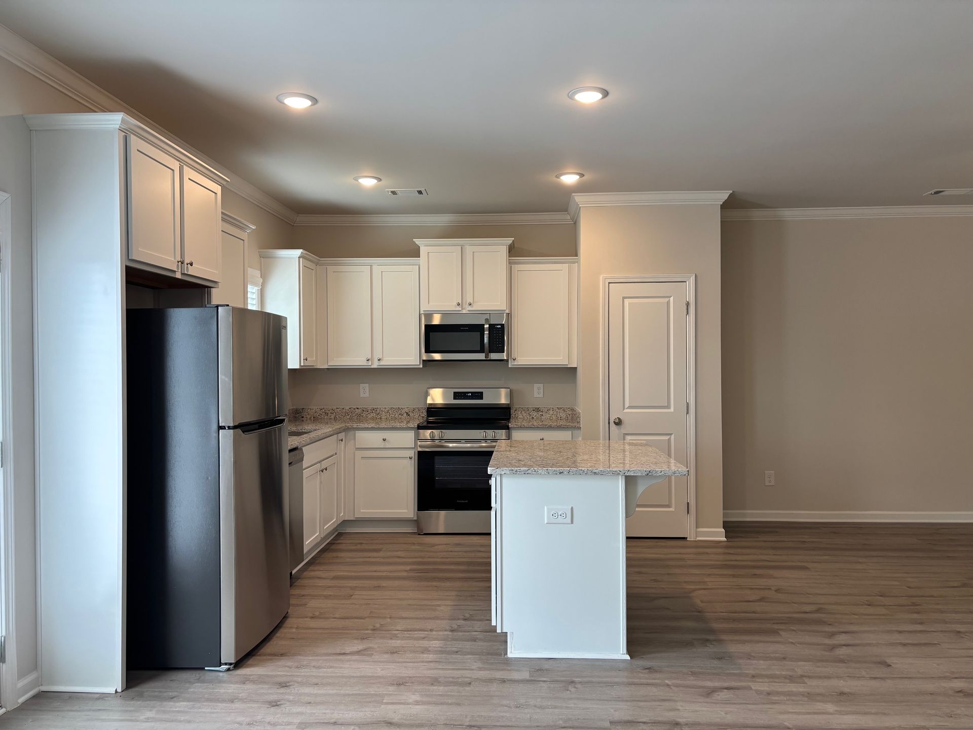 Bright modern kitchen with white cabinets, stainless steel appliances, and an island in an open living area